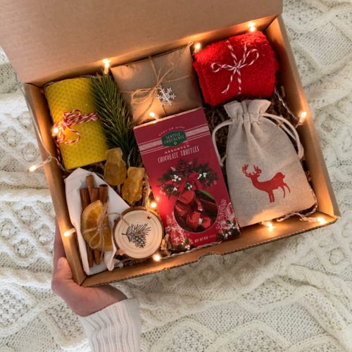 Christmas gift box filled with chocolate truffles, potpourri, cozy socks, and fairy lights