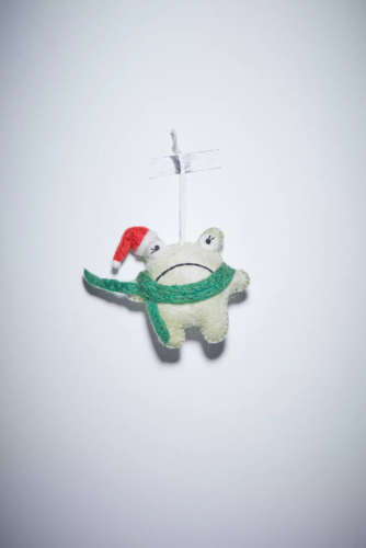 Photo of a gray frowning frog Christmas ornament made out of felt with a santa hat and scarf
