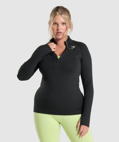 Photo of a blonde woman wearing light green leggings and a black Gymshark half zip long sleeve jacket
