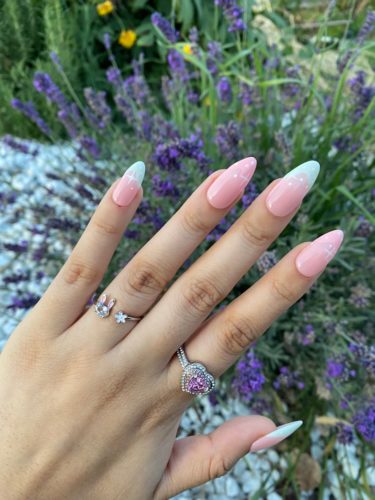 Photo of a pink manicure with pink and green alternating french tips and sparkle star nail art in white