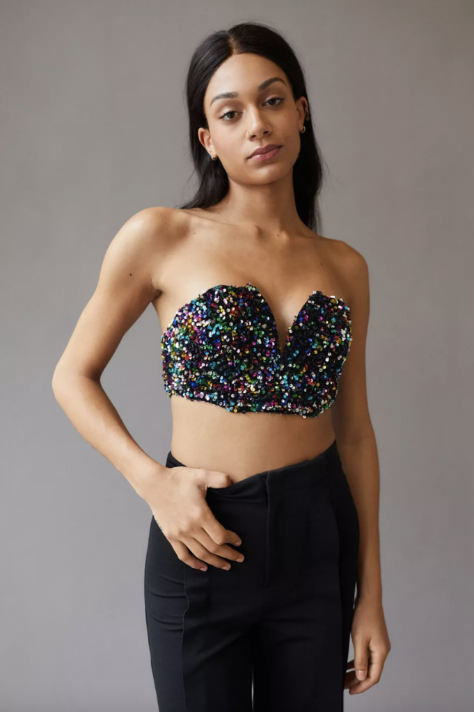 Photo of a model wearing a black and rainbow sequin strapless bustier with black jeans