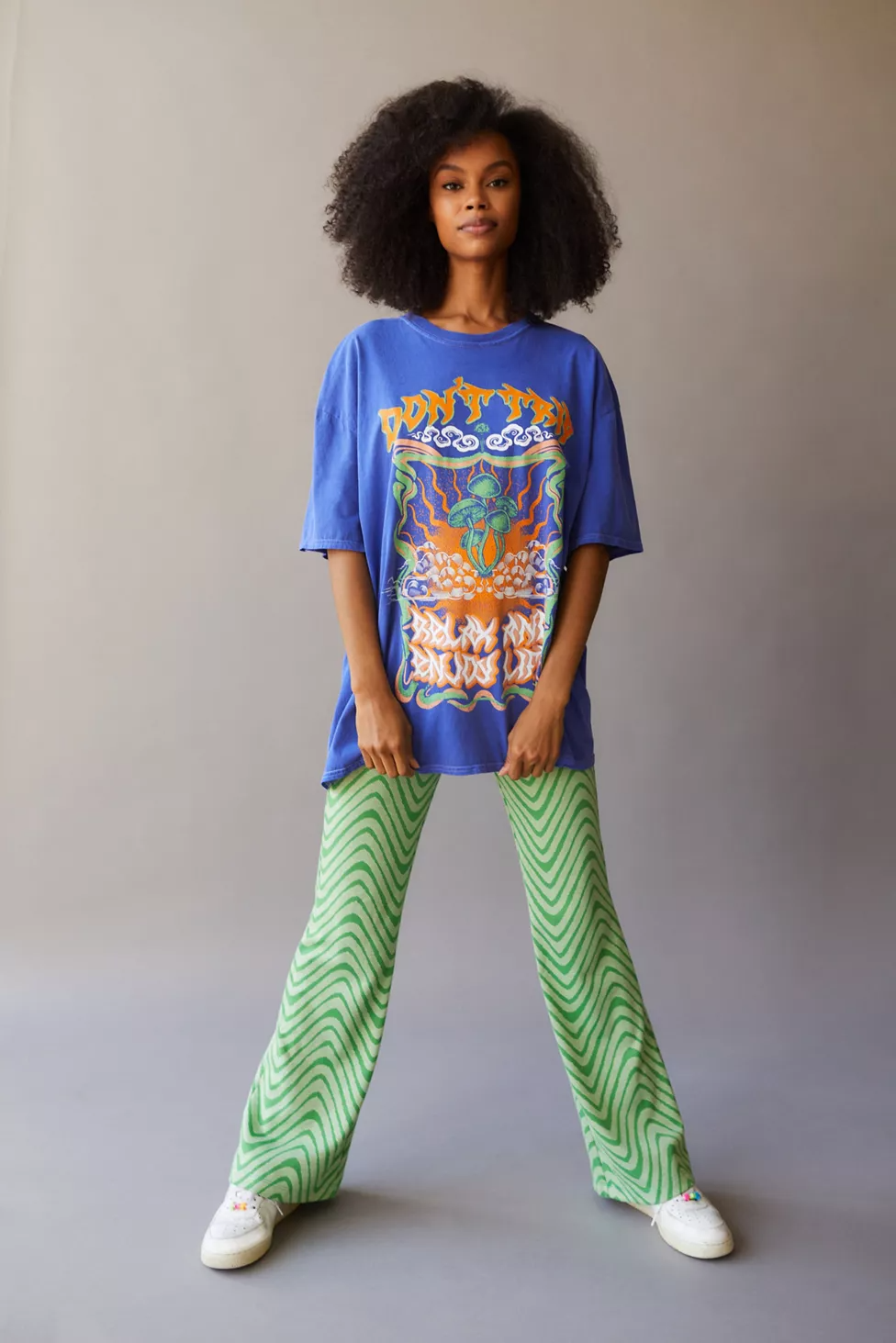 A girl standing wearing a semi-oversized mixing bold colors t-shirt and pants on a white sneakers.