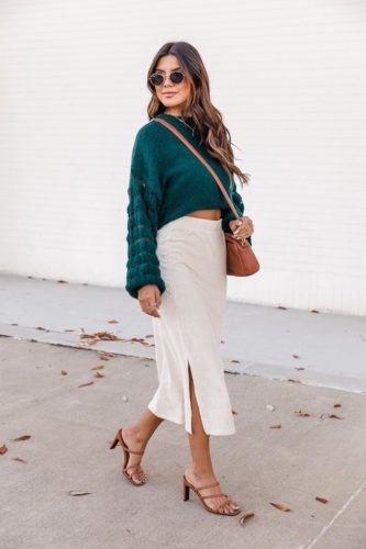 Casual cool Christmas outfit with cream velvet midi skirt, cropped dark green sweater, camel strappy heels, camel bag