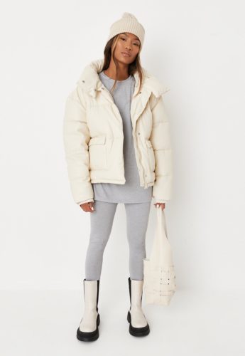 Cute leggings outfit for winter: Gray leggings, gray oversized long-sleeve tee, cream puffer coat, cream and black boots, cream beanie hat