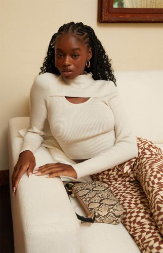 Cute vibey outfit with patterned pants, snakeskin mini bag, and cream cutout sweater