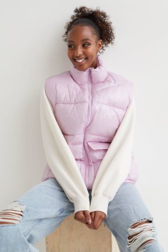 Puffer vest outfit for winter with white long-sleeve sweatshirt, ripped wide leg jeans in a light wash, and lavender puffer vest