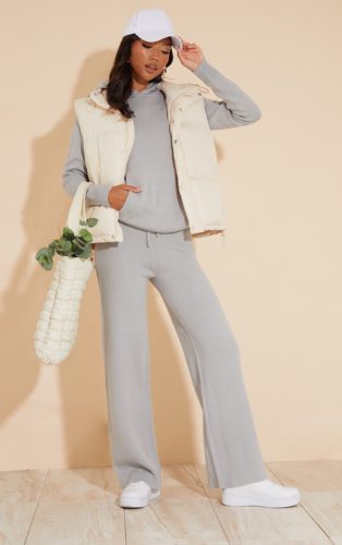Lounge outfit for winter with gray matching set of pants and hoodie, cream puffer vest, white baseball cap, and white sneakers
