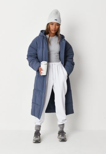 Missguided Longline Puffer in blue paired with a basic pair of white sweatpants, a gray long-sleeve t-shirt, a gray beanie, and gray sneakers and socks