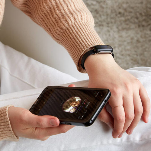 Photo of a model wearing long distance touch bracelet and accessing the bracelet's iphone app