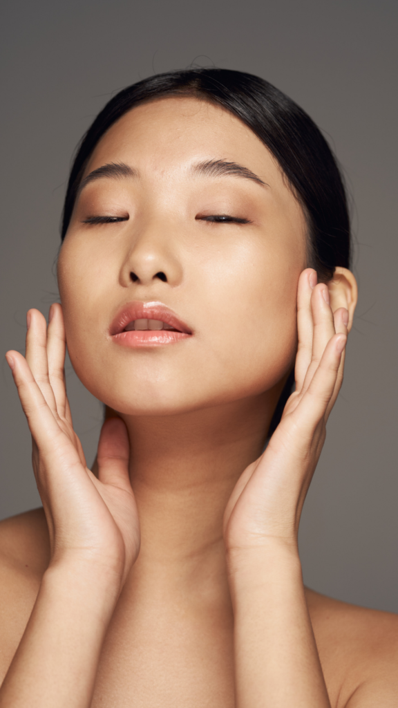 Image of a woman wearing natural makeup touching her face