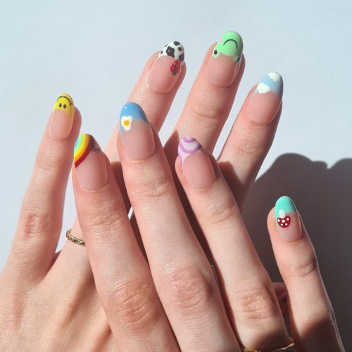 Nude nails with multicolored french tips and designs including swirls, frog nail art, smiley faces, and rainbows