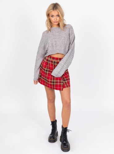 Christmas outfit with plaid skirt, cropped gray sweater, and chunky black ankle boots