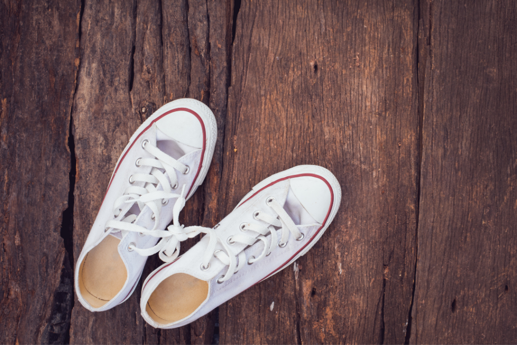 Photo of white converse sneakers on a wood floor