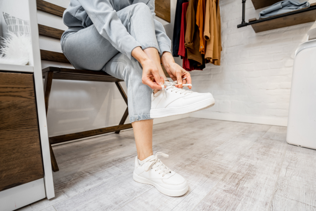 Photo of a woman putting on a pair of white sneakers