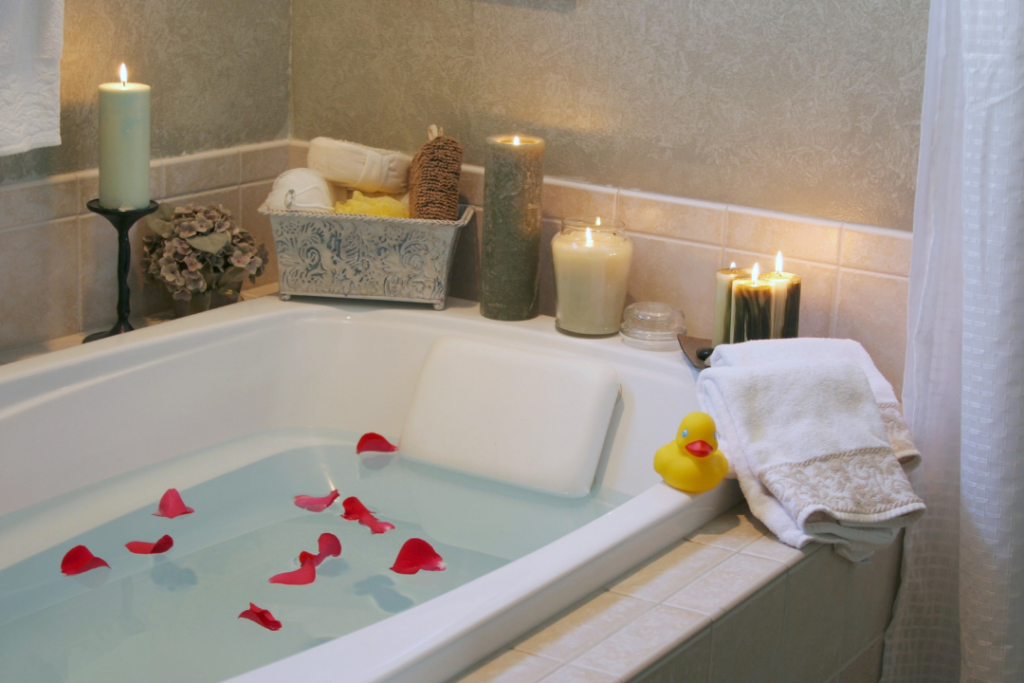 Photo of a bathtub filled with water and rose petals, surrounded by candles