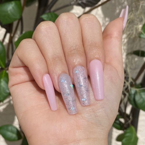 Light pink nails with holographic glitter and iridescent stars