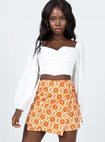 Princess Polly Orange Skirt with sunburst pattern paired with a white gathered long sleeve crop top