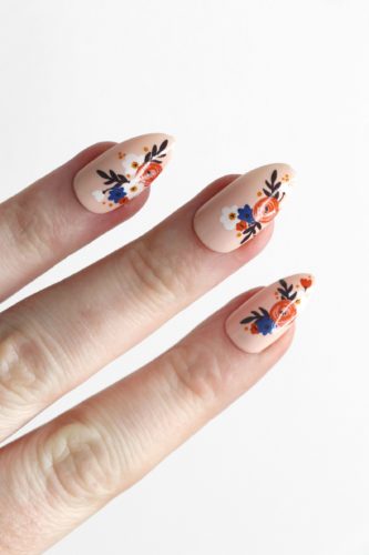 Modern floral nails in peach beige with blue and orange flower detailing