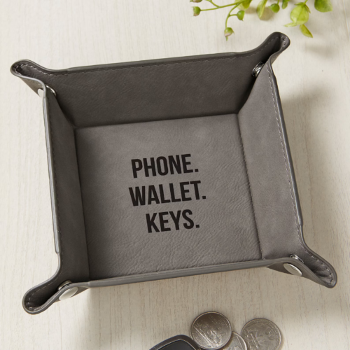 Square shaped leather valet that reads Phone. Wallet. Keys.