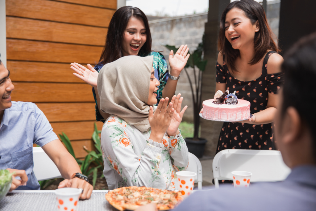 Photo of women surprising the birthday girl with a pink cake