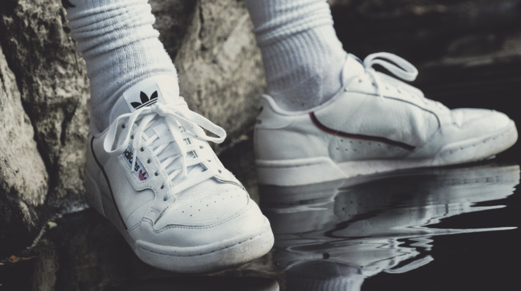 Photo of two feet in white Adidas Superstar sneakers with crew socks.