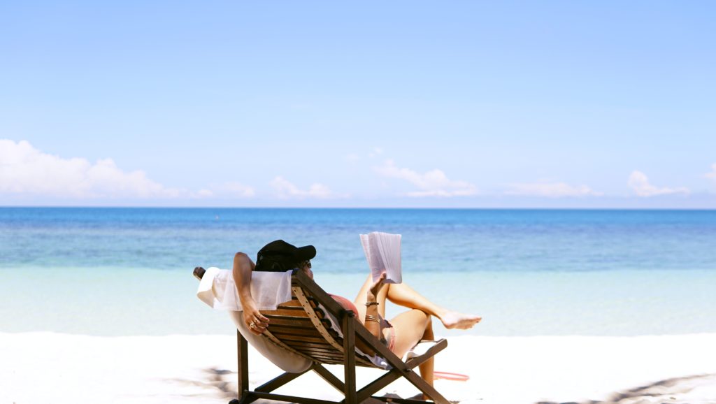 photo of a woman reading on the beach from unsplash - summer bucket list ideas
