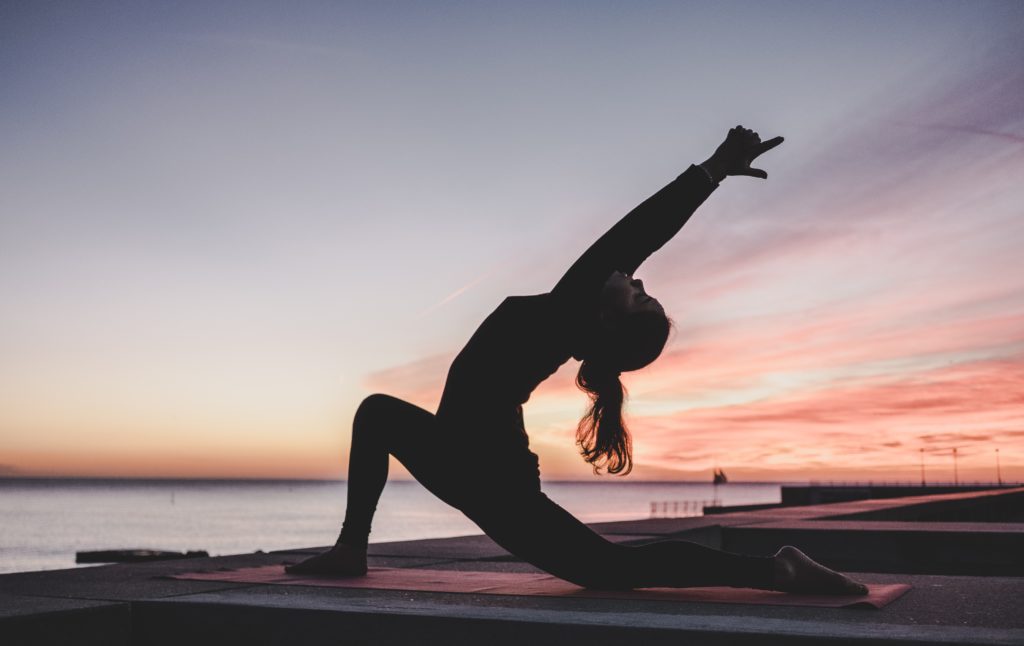 Woman doing yoga in front of a sunset photo from unsplash