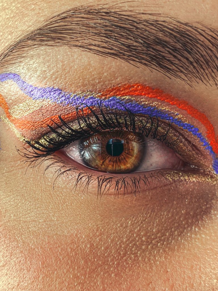 Closeup photo of an eye with red, blue, and gold liner.