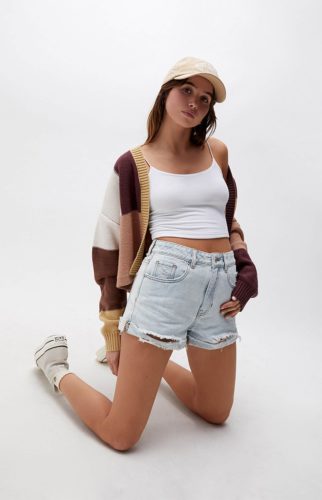 Pacsun Jean Shorts paired with a white crop top, striped cardigan, cream Converse high tops, and yellow baseball hat
