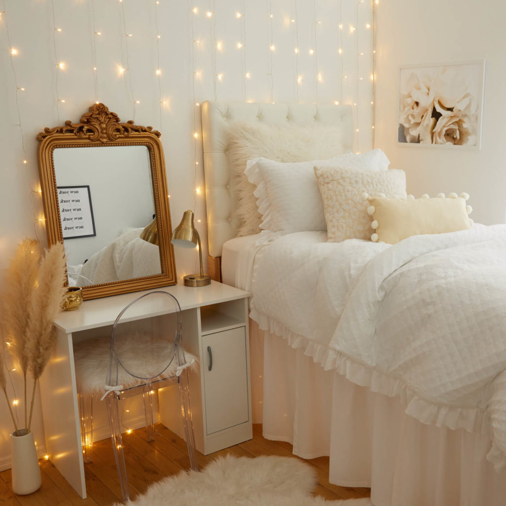 Glam golden room from Dormify with string lights and frilly white bedding