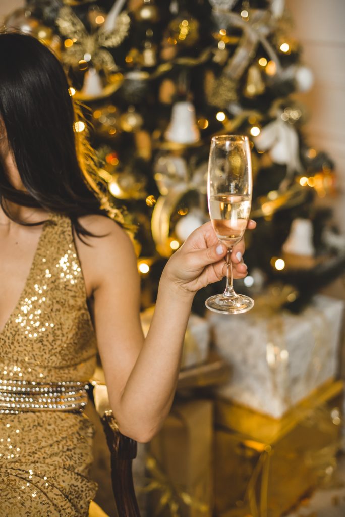 Photo of a woman wearing a gold dress drinking champagne from unsplash - 20th birthday ideas