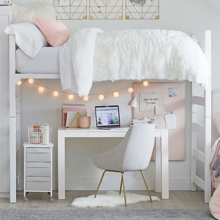 Cute dorm room with a study space beneath a lofted bed, decorated with a pinboard and hanging lights
