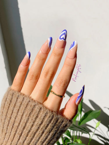 Purple and white heart swirl nails in an almond shape