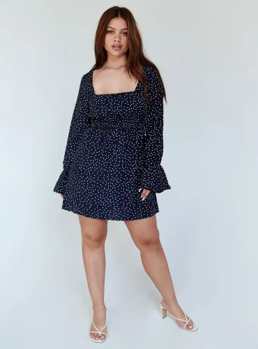 A navy polka dot mini dress and white strap heels.