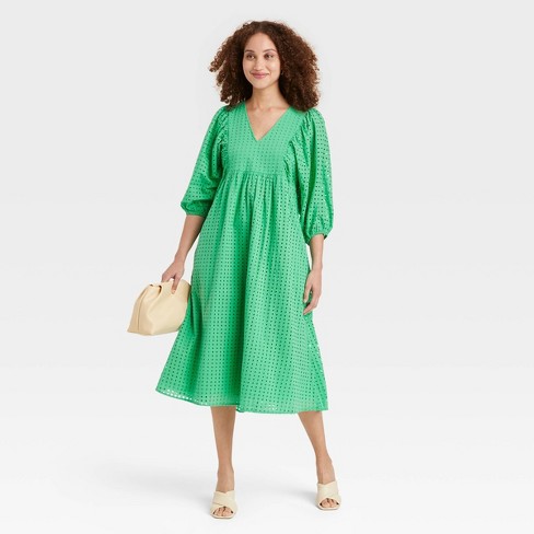 A green eyelet balloon sleeve midi dress, nude shoulder bag and nude mules.