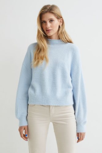 A light blue sweater and cream denim jeans.