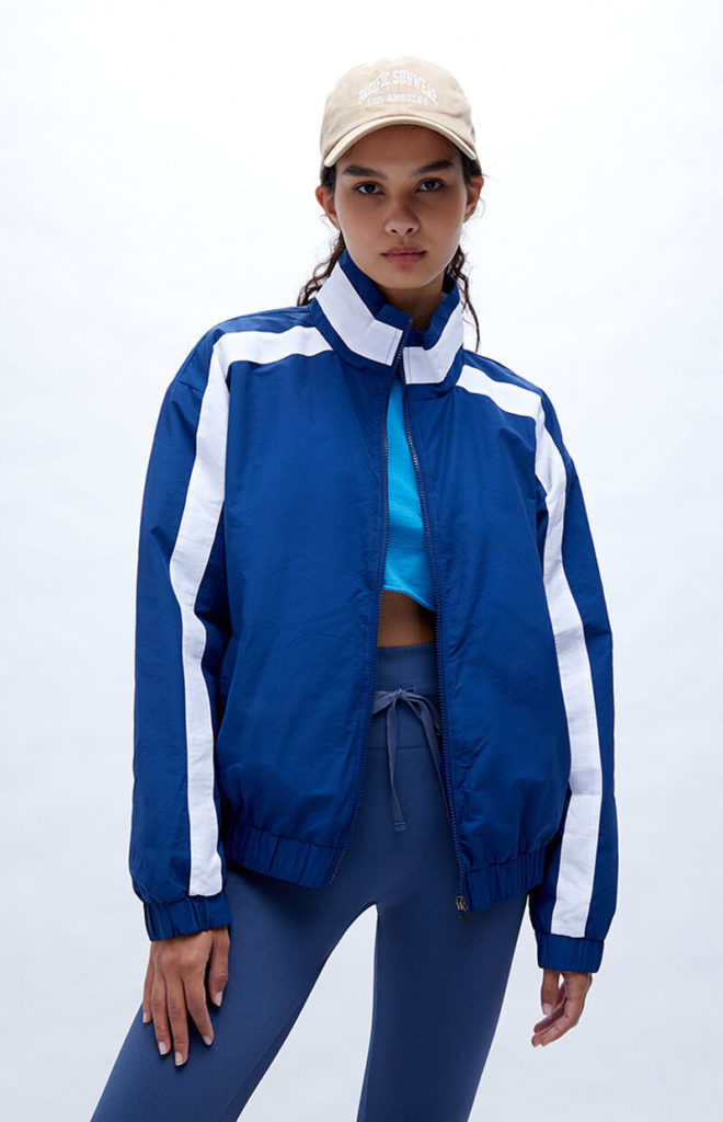 A navy track jacket, tan baseball cap, blue crop tee and blue leggings.