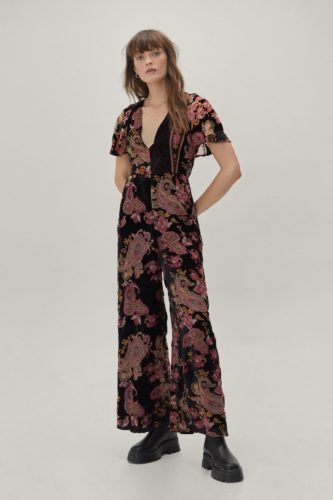 A paisley print wide leg jumpsuit and black boots.