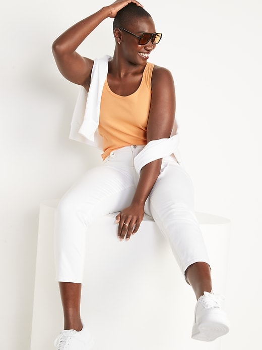 A mango color tank top, white sweatshirt, white pants, white sneakers and sunglasses.