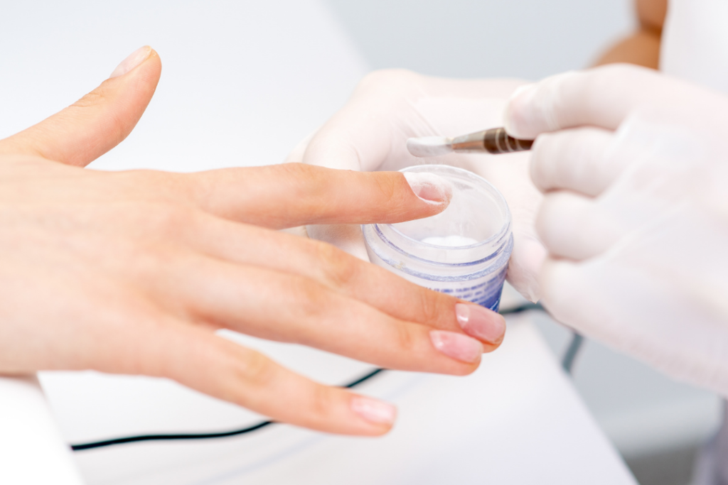 Photo of a woman having dip nails powder applied to her nails