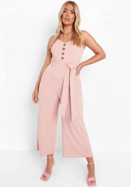 A pink button culotte jumpsuit with belt and pink strappy heels.