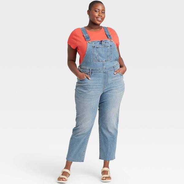 A bright orange tee, denim overalls and tan sandals.