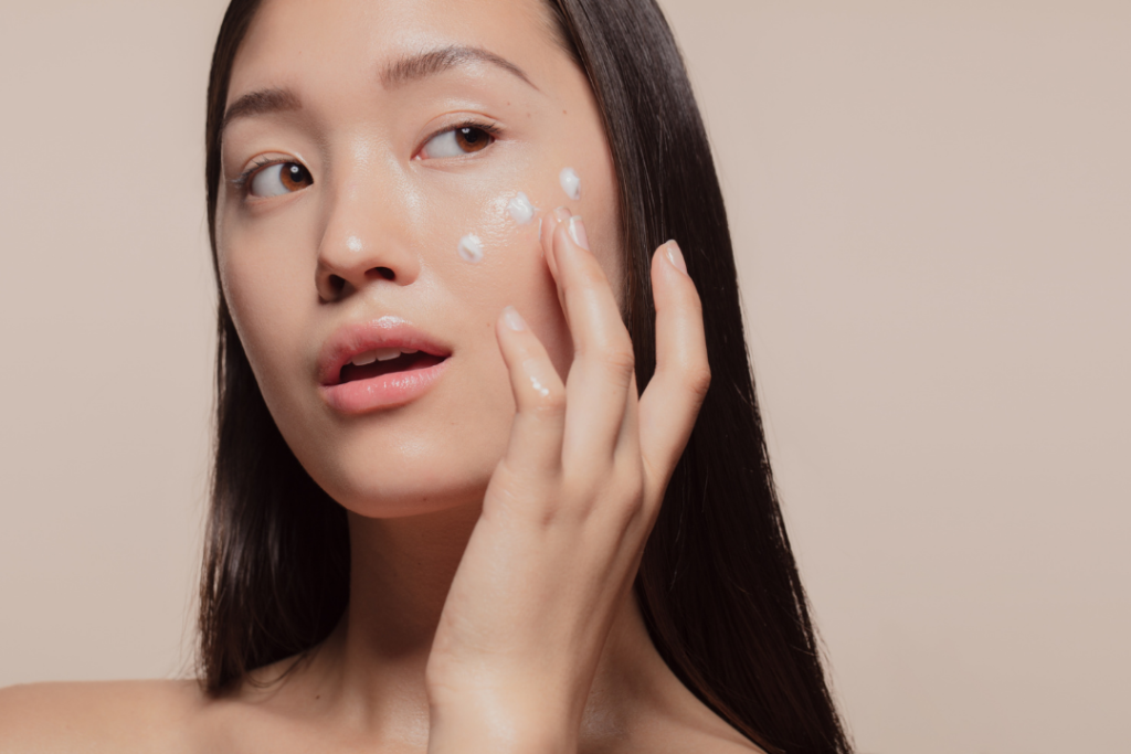 Woman applying three dots of korean moisturizer to her cheeks