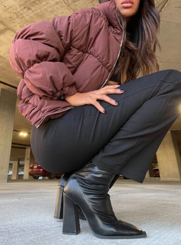 A burgundy puffer jacket, black pants, black crop top and black ankle boots.