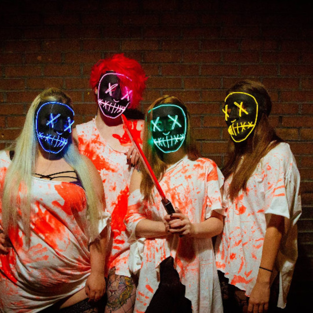 A group of four best friends dressed as characters from The Purge with light up masks and bloody white shirts