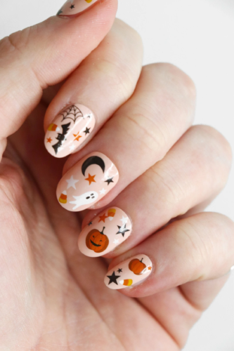 Short halloween nails with pale orange base and bat, candy corn, star, pumpkin, and ghost decals
