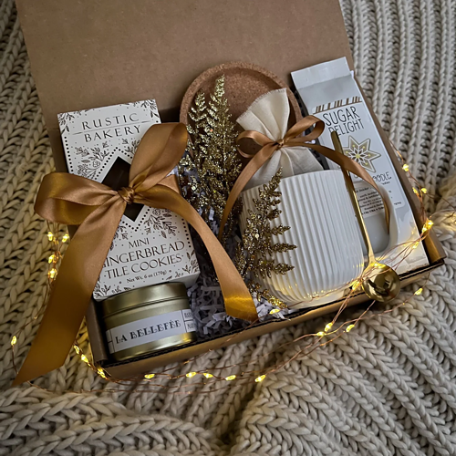 Christmas gift box with mini gingerbread cookies, tea, mug, golden tea spoon, sea salt caramels, and fairy lights