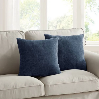 two navy blue pillows on a gray couch
