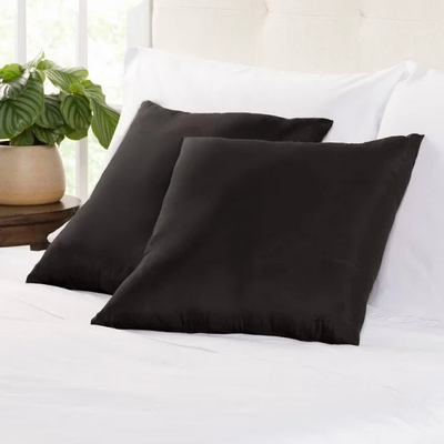 two soft shingt black pillows on a minimalistic white bed and background
