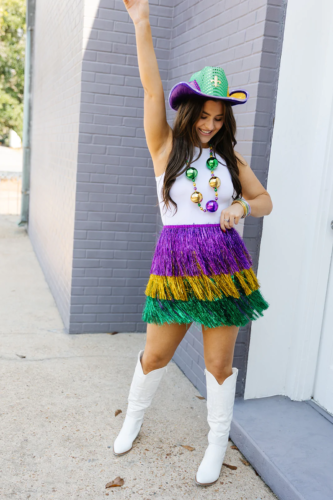 Glitter fringe Mardi Gras skirt paired with white bodysuit, cowboy hat, white boots, and Mardi Gras beads